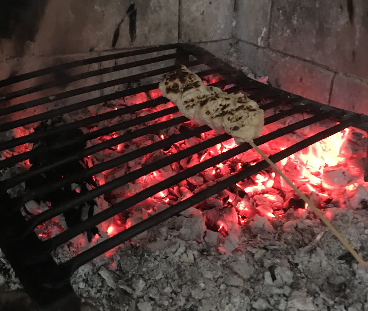 En bit så kallat pinn-bröd som grillas över en lppen eld.